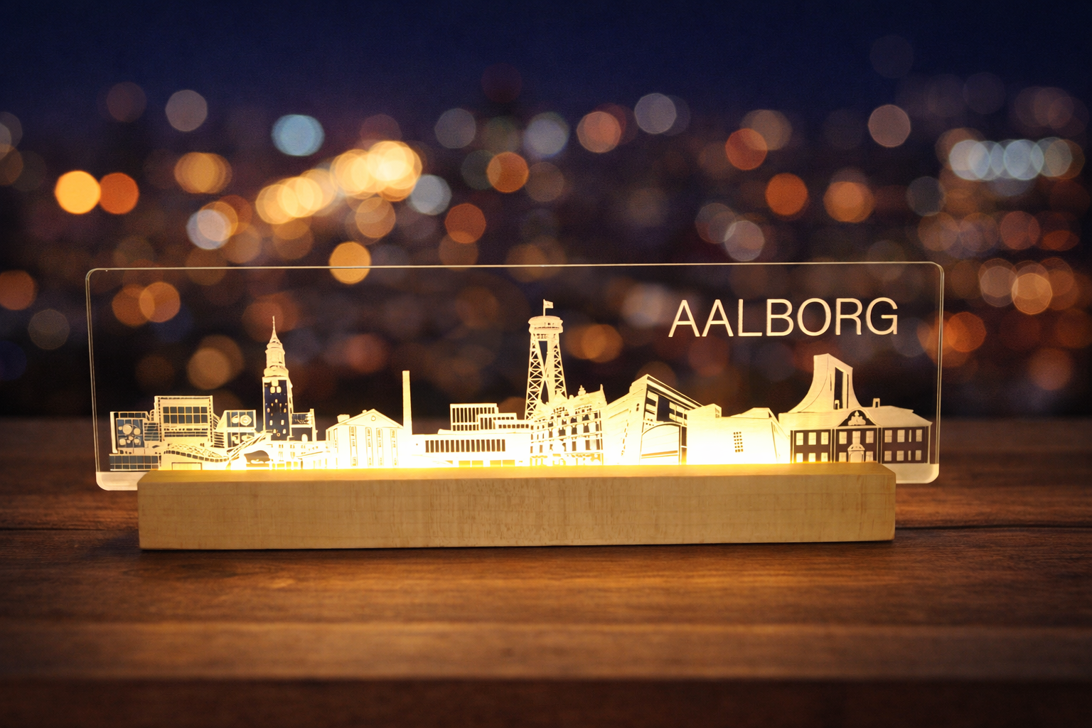 A acrylic LED night light featuring a laser-cut silhouette of Aalborg's skyline, illuminated from within to cast a warm golden glow.